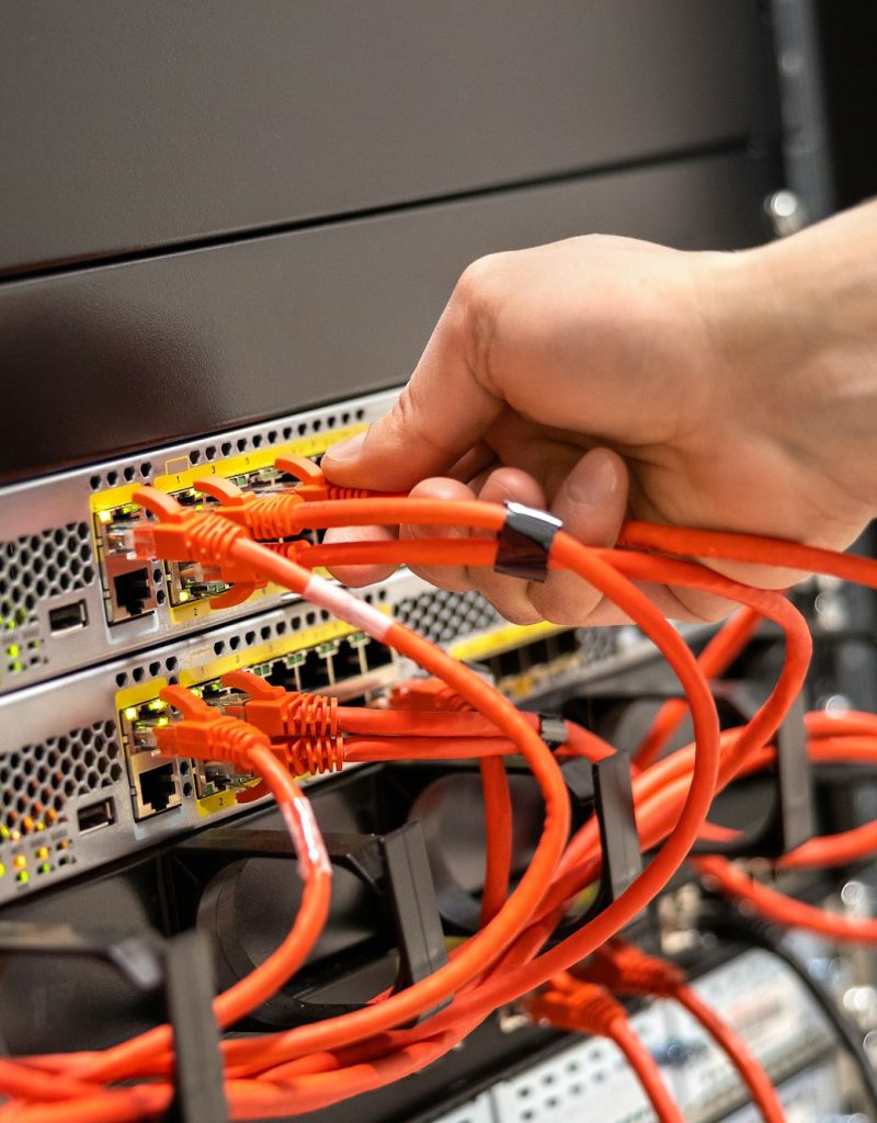 Close-up of Male Technician Plugging Network Cable In Network Router Close-up of Male Technician Plugging Network Cable In Network Router